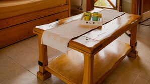 Um banco de madeira com uma mesa na frente, uma janela com vista e uma porta que dá para o exterior.