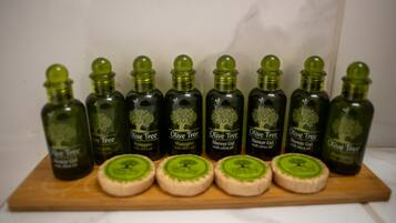 A wooden board with eight bottles of Olive Tree products and four soaps.