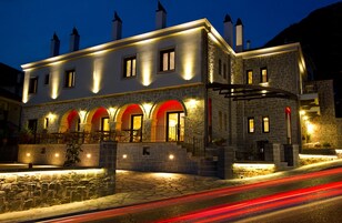 Edificio de piedra con múltiples arcos y un vestíbulo cubierto, iluminado con una luz cálida.