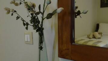 A room with a large mirror, a vase with flowers, and a sign on the wall.