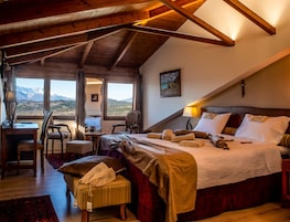 Un dormitorio acogedor con una cama grande, un escritorio y una silla, con vistas a la montaña a través de una ventana.