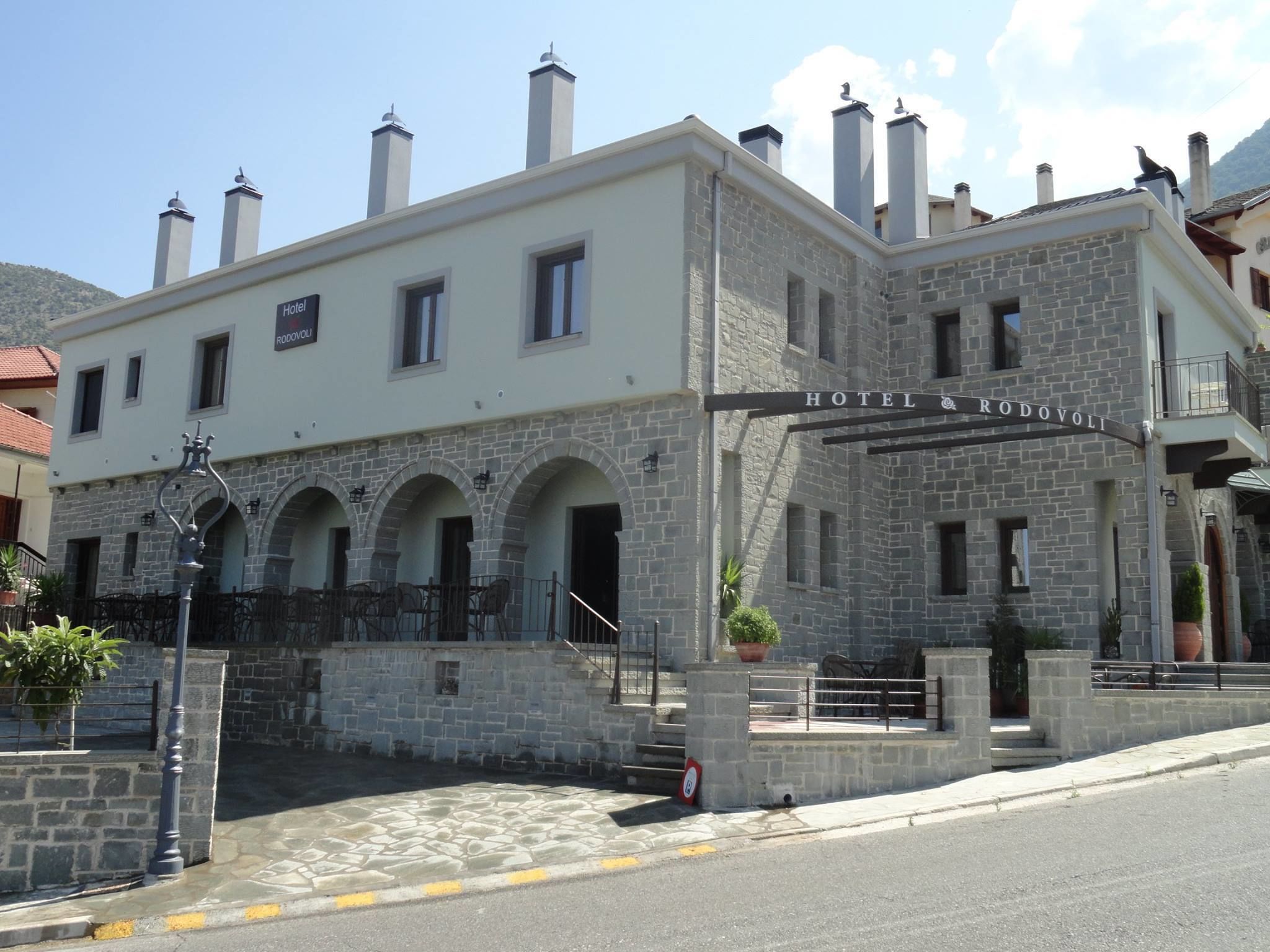 A hotel with a stone facade, multiple chimneys, and a sign reading "HOTEL A RODOVOLI".