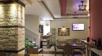Una sala de estar moderna con una pared de acento de piedra, una chimenea, un comedor con mesa y sillas, y un televisor montado en la pared.