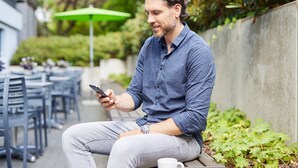 A person sitting on a bench outdoors, using a smartphone. - appartello - smarttime living Hamburg (Hamburg)