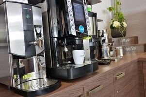 Una máquina de café comercial con varios dispensadores, una pantalla digital y una taza de café sobre el mostrador.