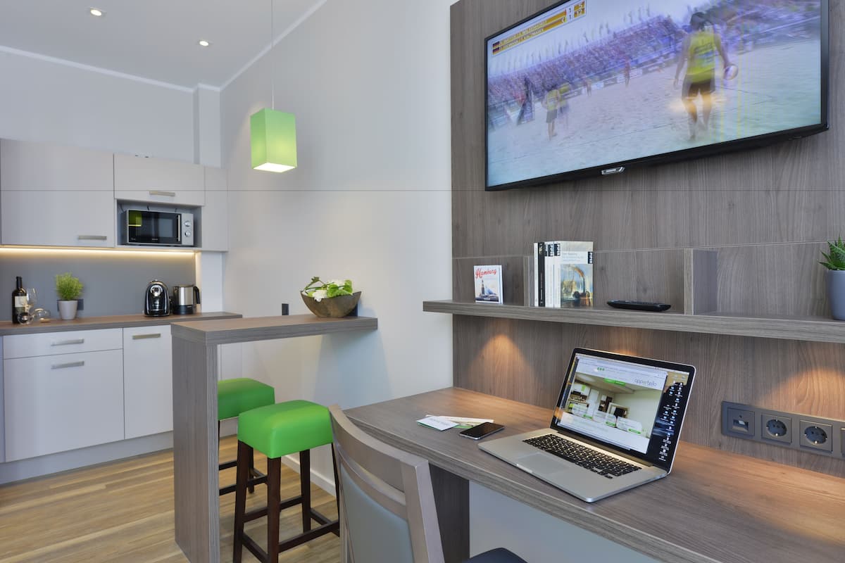 Une cuisine moderne équipée d’un four à micro-ondes, d’une machine à café et d’un tabouret vert.