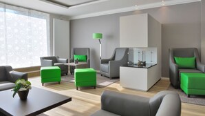 A modern living room with grey sofas, green ottomans, a white coffee table, and a floor lamp. - appartello - smarttime living Hamburg (Hamburg)