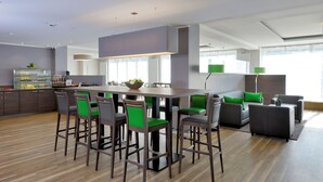 A modern kitchen with a central island, bar stools, and a dining area with a sofa and chairs. - appartello - smarttime living Hamburg (Hamburg)