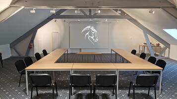 A conference room with a long table, black chairs, a whiteboard with a horse silhouette, and a fire extinguisher.