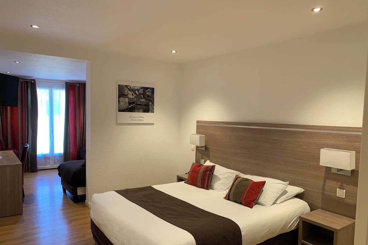 A hotel room with a bed, bedside tables, a desk, and a chair.