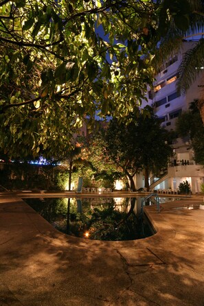 A nighttime outdoor area with a pool, lounge chairs, and a staircase leading to an upper level. - Chellah Hotel (Tangier)