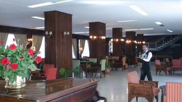 A spacious lobby with a grand piano, comfortable seating, and a staircase in the background.