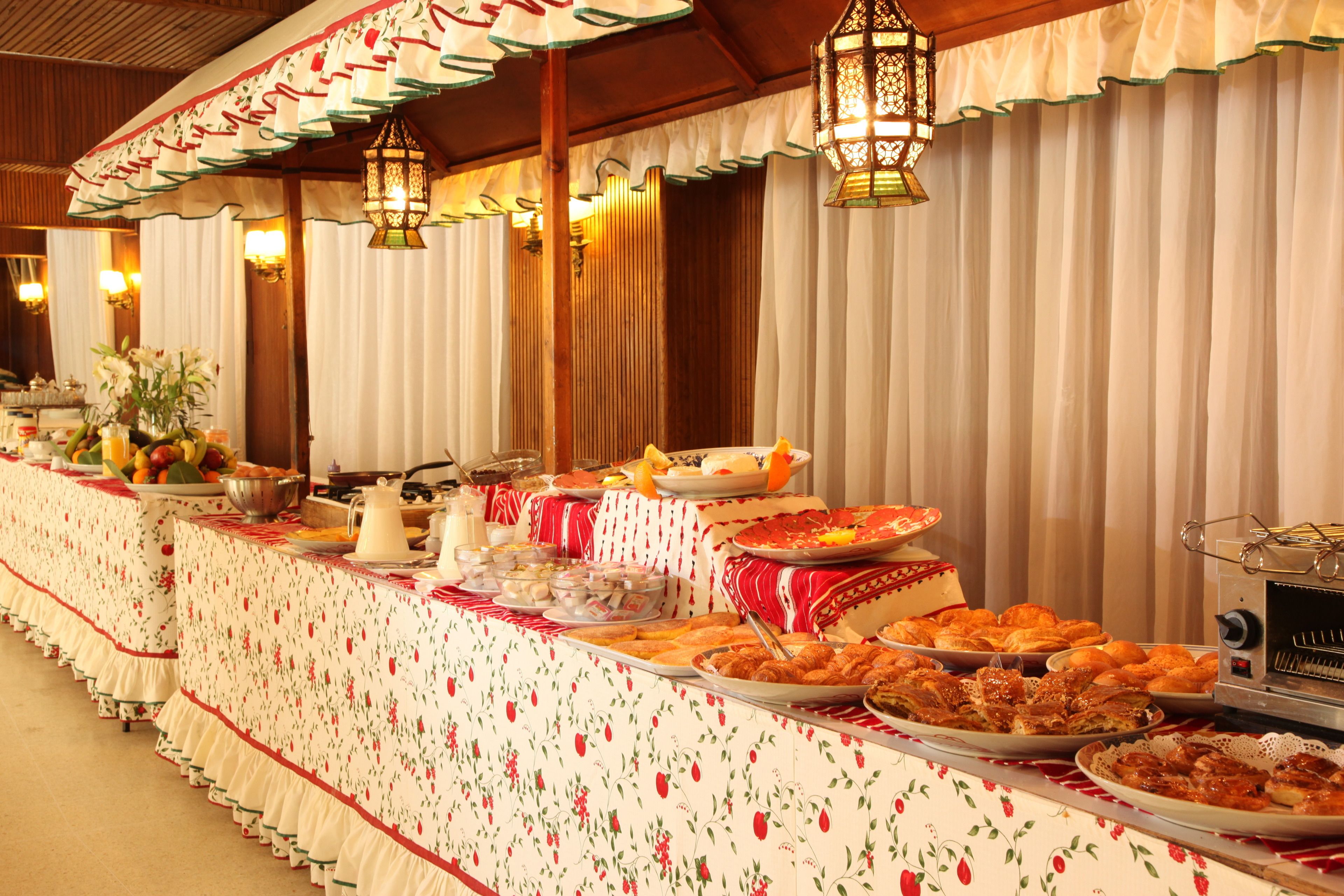 Mesa de buffet com diversos pratos, um coador de café e uma torradeira.
