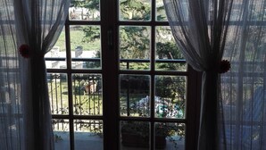 Une fenêtre donnant sur un jardin et un bâtiment situé de l’autre côté de la rue.