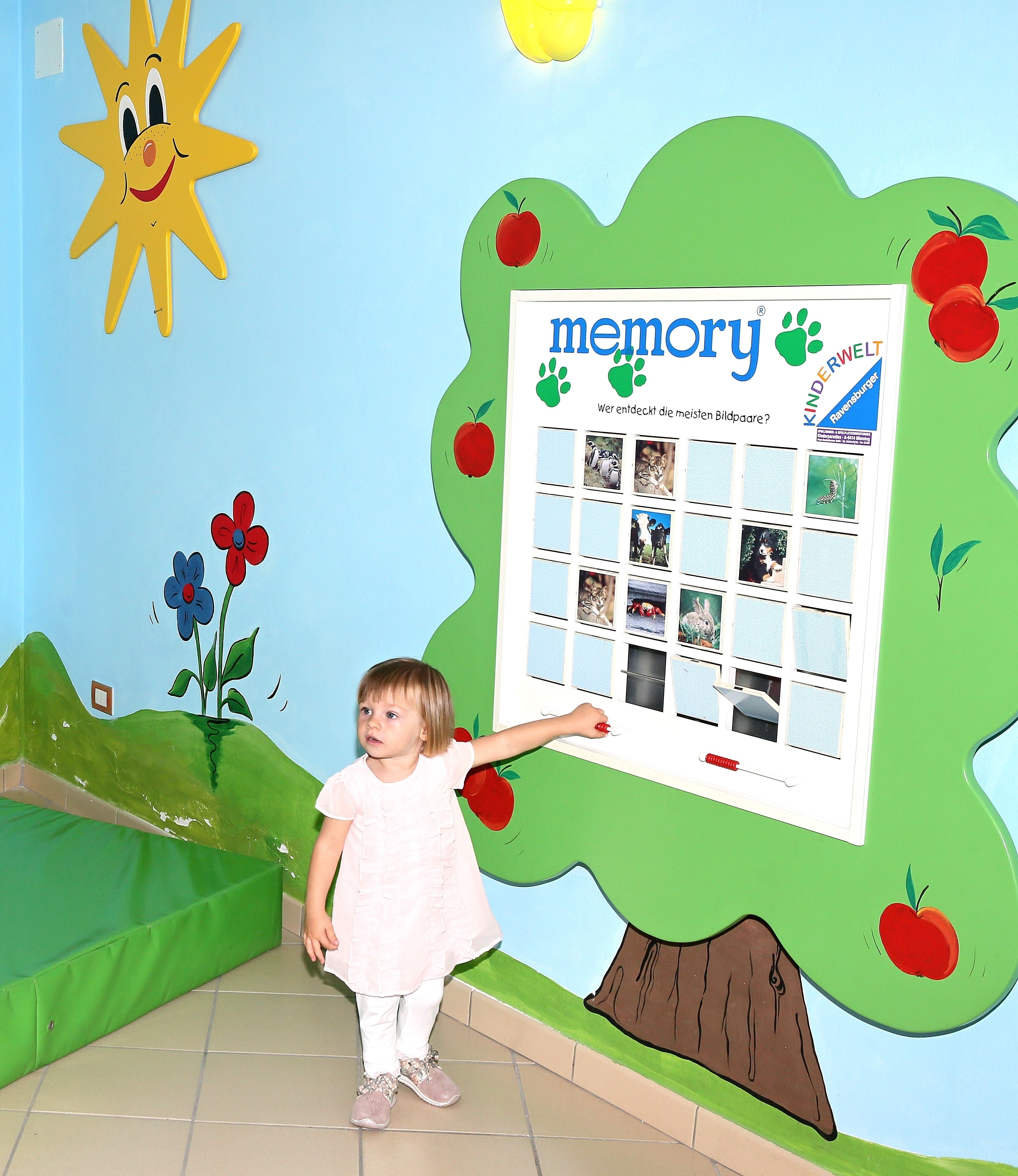 A child pointing at a memory board with pictures and text.
