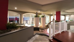 A modern indoor garden with a wooden deck, large planters, and a view of the outside. - Hotel Mediterranee Family & Spa Hotel (San Michele al Tagliamento)