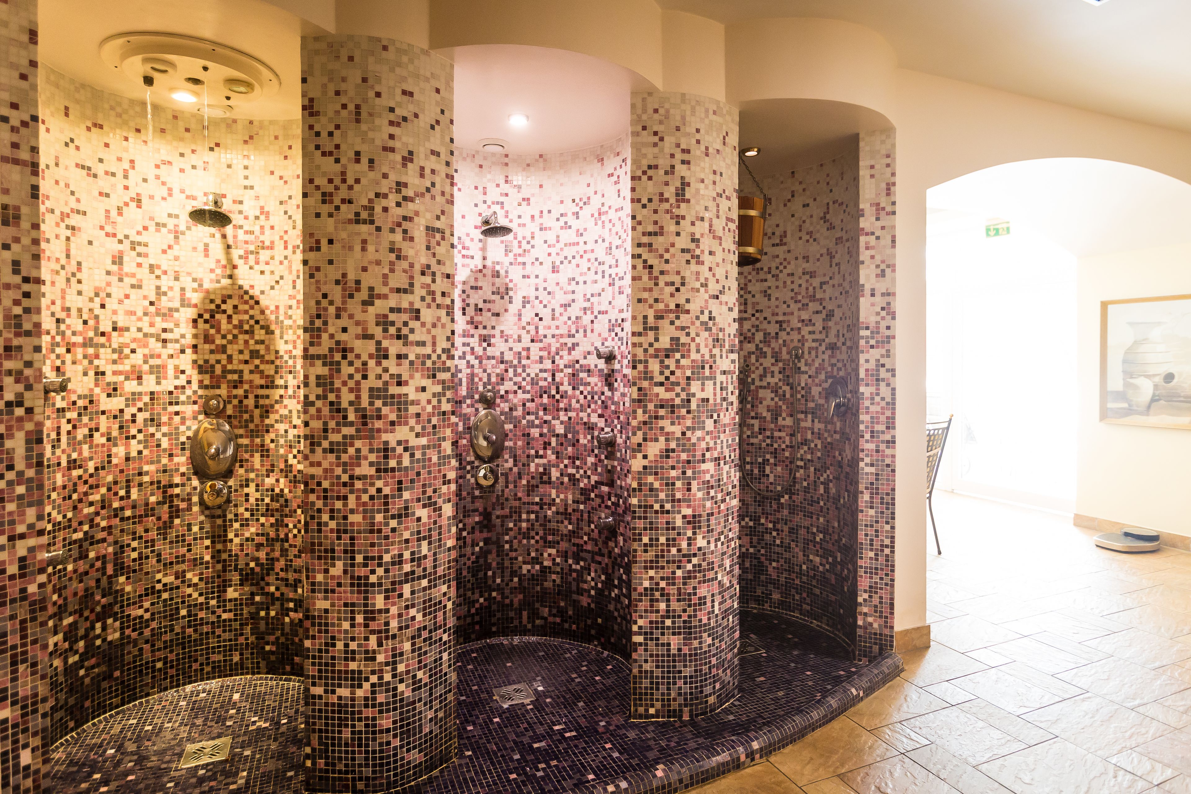 A mosaic-tiled shower area with multiple columns and a tiled floor.
