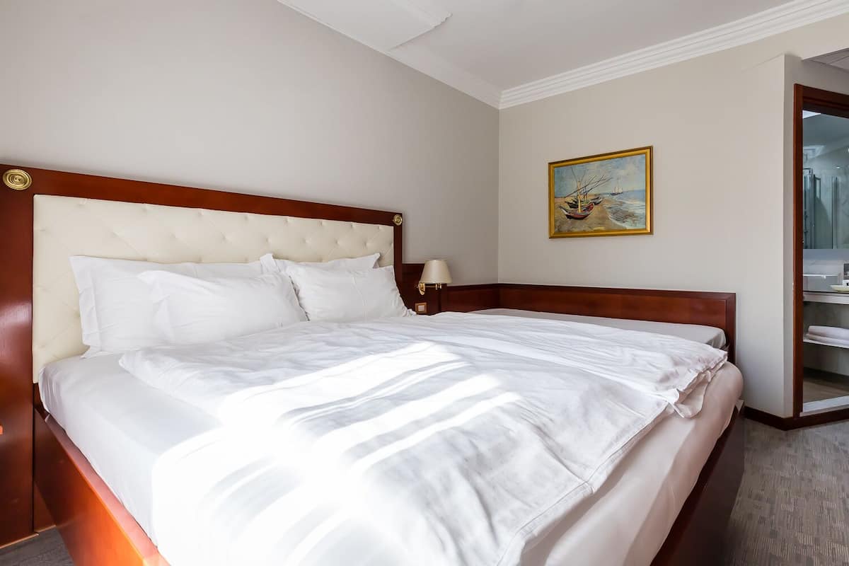 A neatly made bed with white linens in a hotel room.