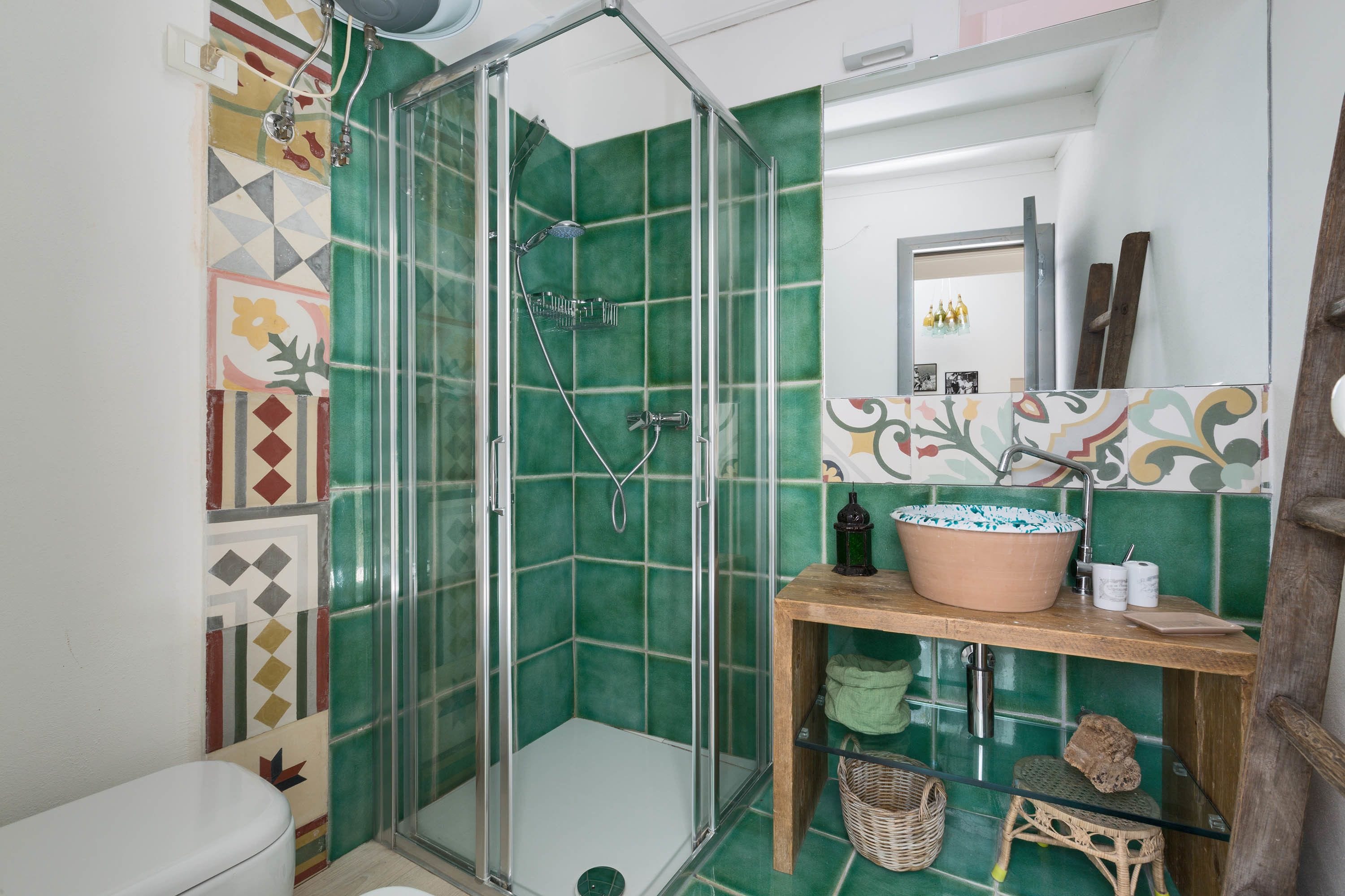 Ein Badezimmer mit einer Duschkabine, einer Toilette, einem Waschbecken mit dekorativer Schüssel und einem Spiegel über dem Waschbecken.