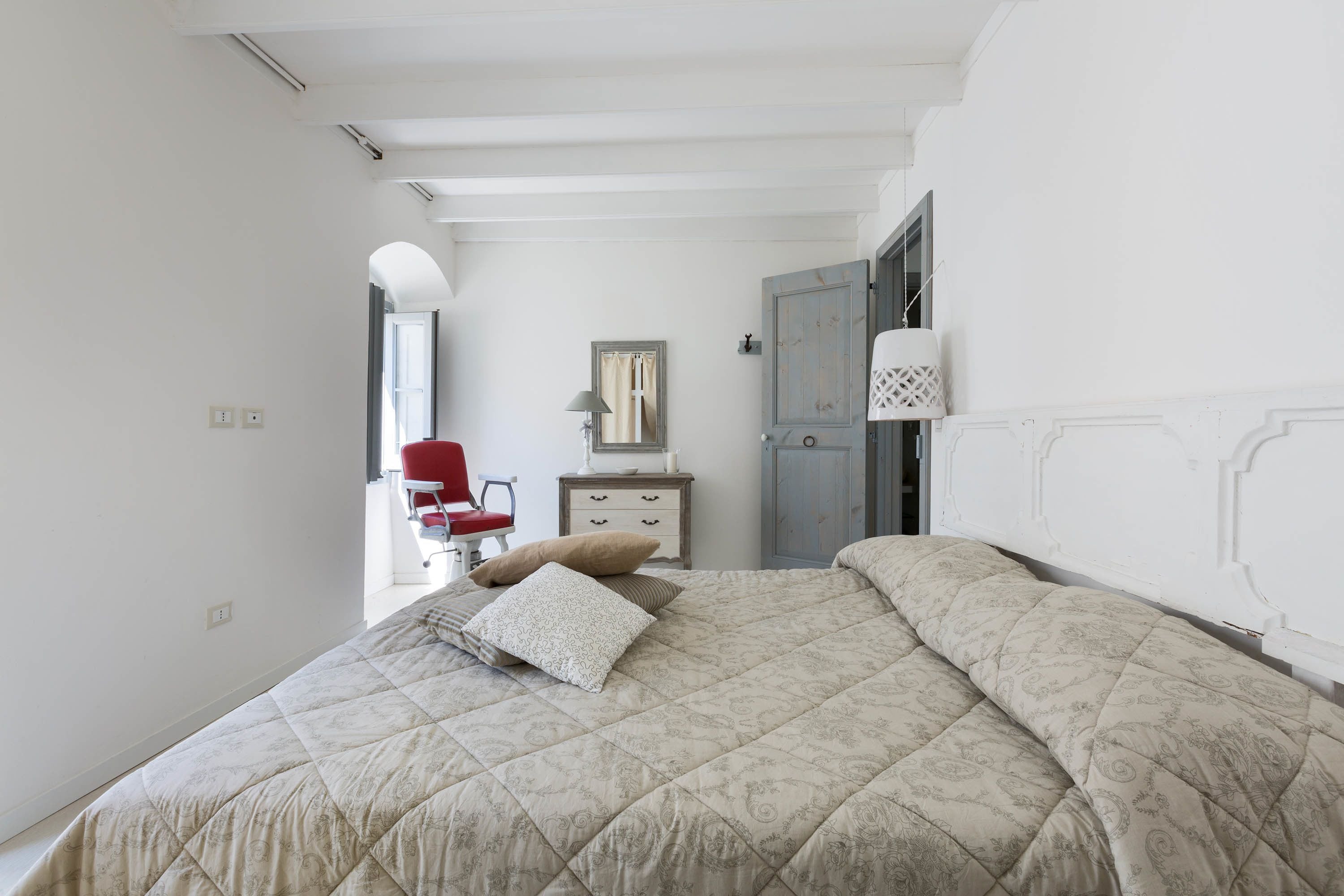 Et soveværelse med en stor seng, en kommode, en stol og et garderobeskab.