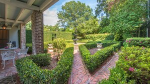 A garden with a brick pathway, white benches, and a fountain. - The Burn Bed and Breakfast (Natchez)