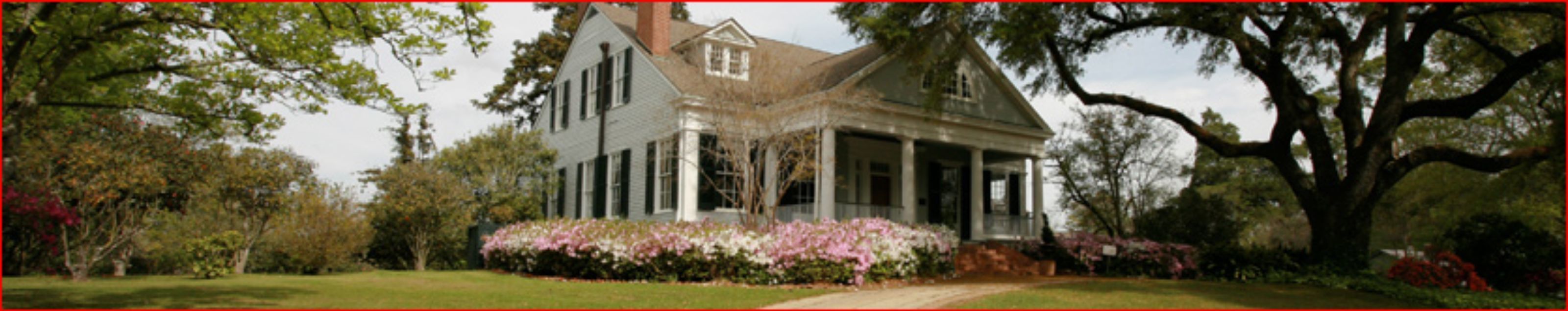 A large, two-story house with a porch and a garden.