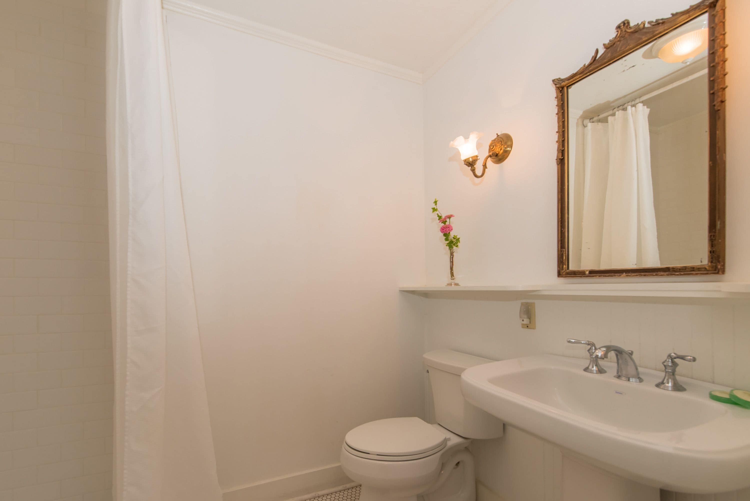 A bathroom with a toilet, sink, and mirror.