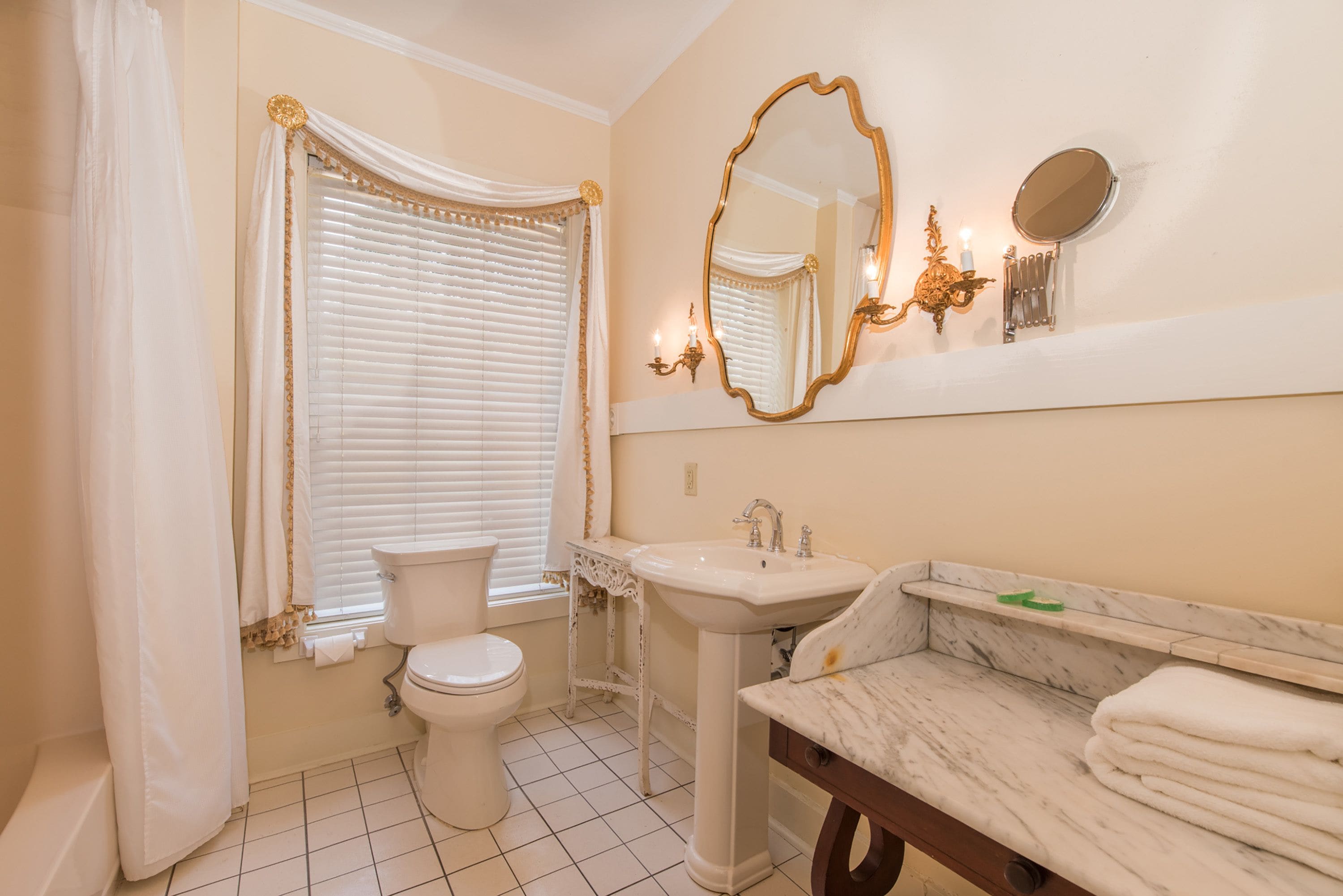 A bathroom with a toilet, sink, vanity, and a large mirror.
