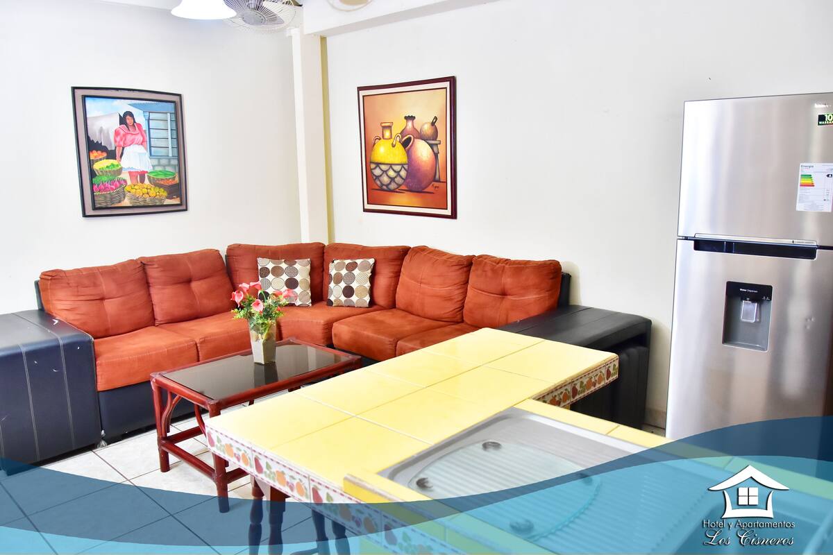 A living room with a brown leather sofa, a yellow coffee table, and a refrigerator.