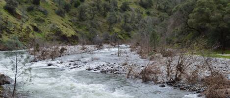 A river flowing through a mountainous area with rocky banks and sparse vegetation.