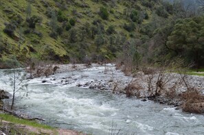 A river flowing through a mountainous area with rocky banks and sparse vegetation.