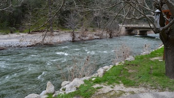 Un río que fluye bajo un puente, con orillas rocosas y vegetación escasa.