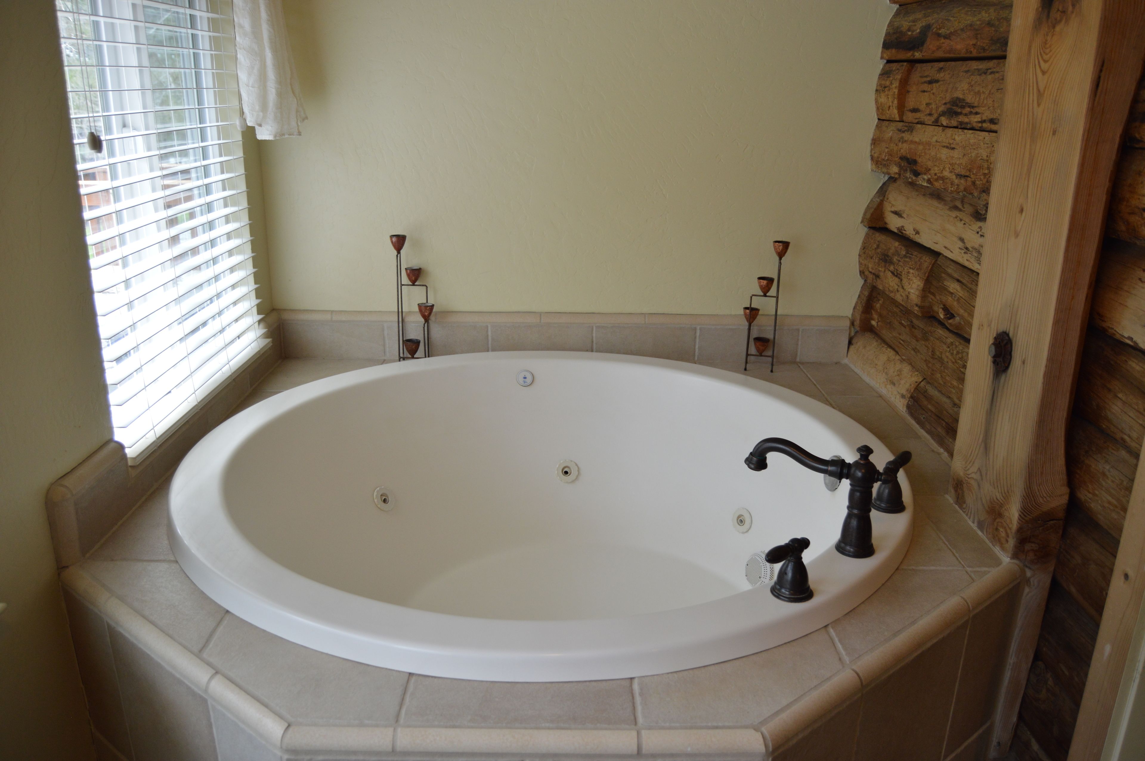 A large oval bathtub with a white interior, two black faucets, and a small control knob.