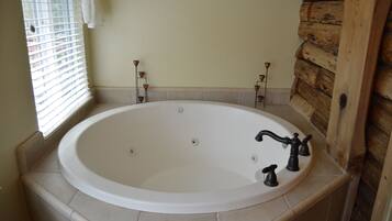 A large oval bathtub with a white interior, two black faucets, and a small control knob.