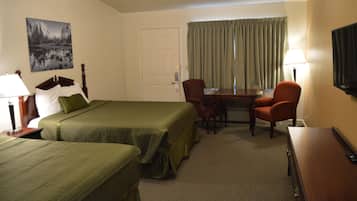 A hotel room with two beds, a desk, a chair, a TV, and a painting on the wall.