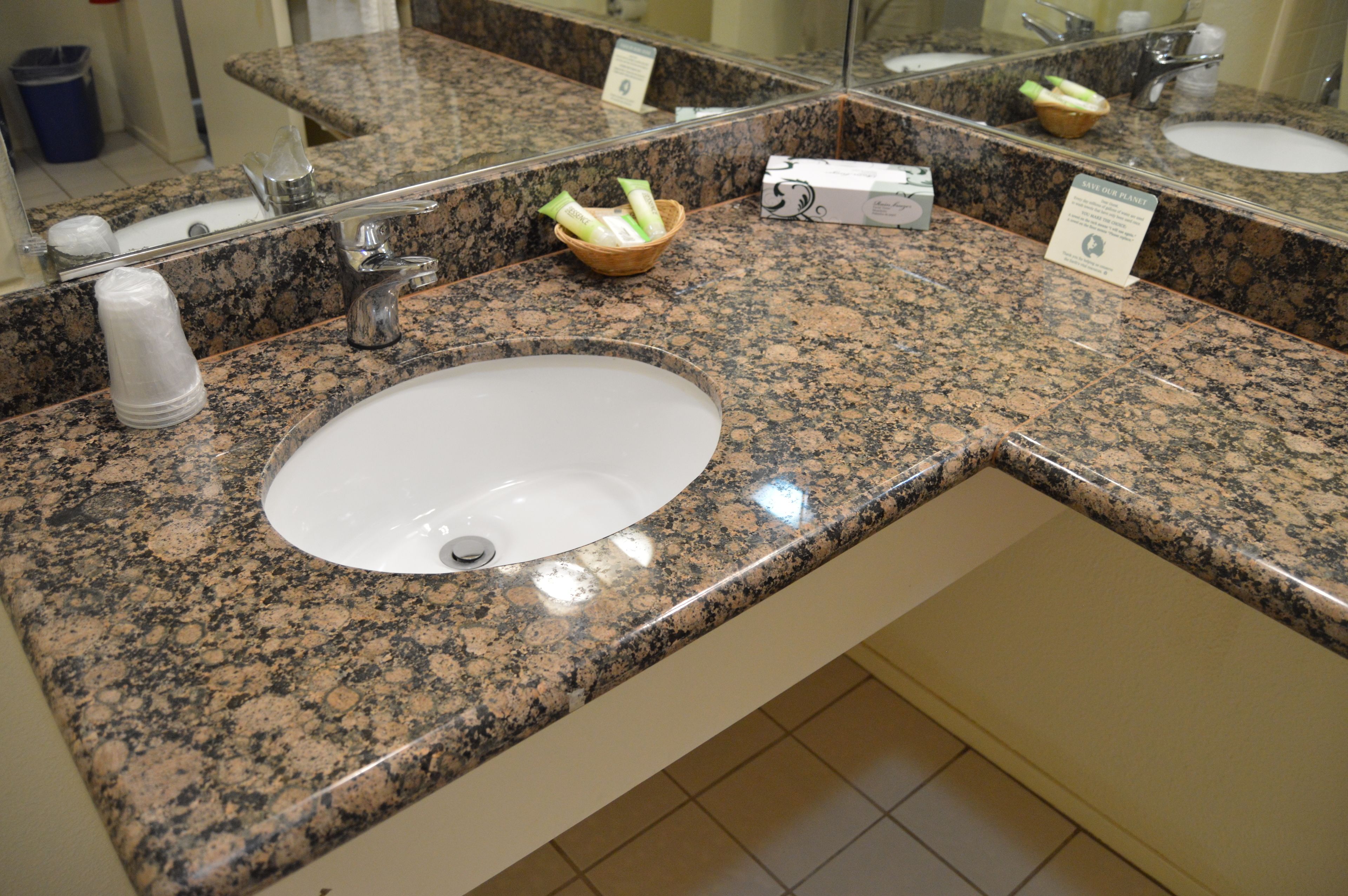 Encimera de granito con un lavabo blanco y un espejo encima.