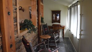 A wooden interior with a stone wall, a wooden door, a mirror, and a small table with chairs. - Red Bud Lodge (El Portal)