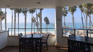 A balcony with a view of the beach and ocean, featuring a table and chairs. - Casa Tropicana (San Clemente)