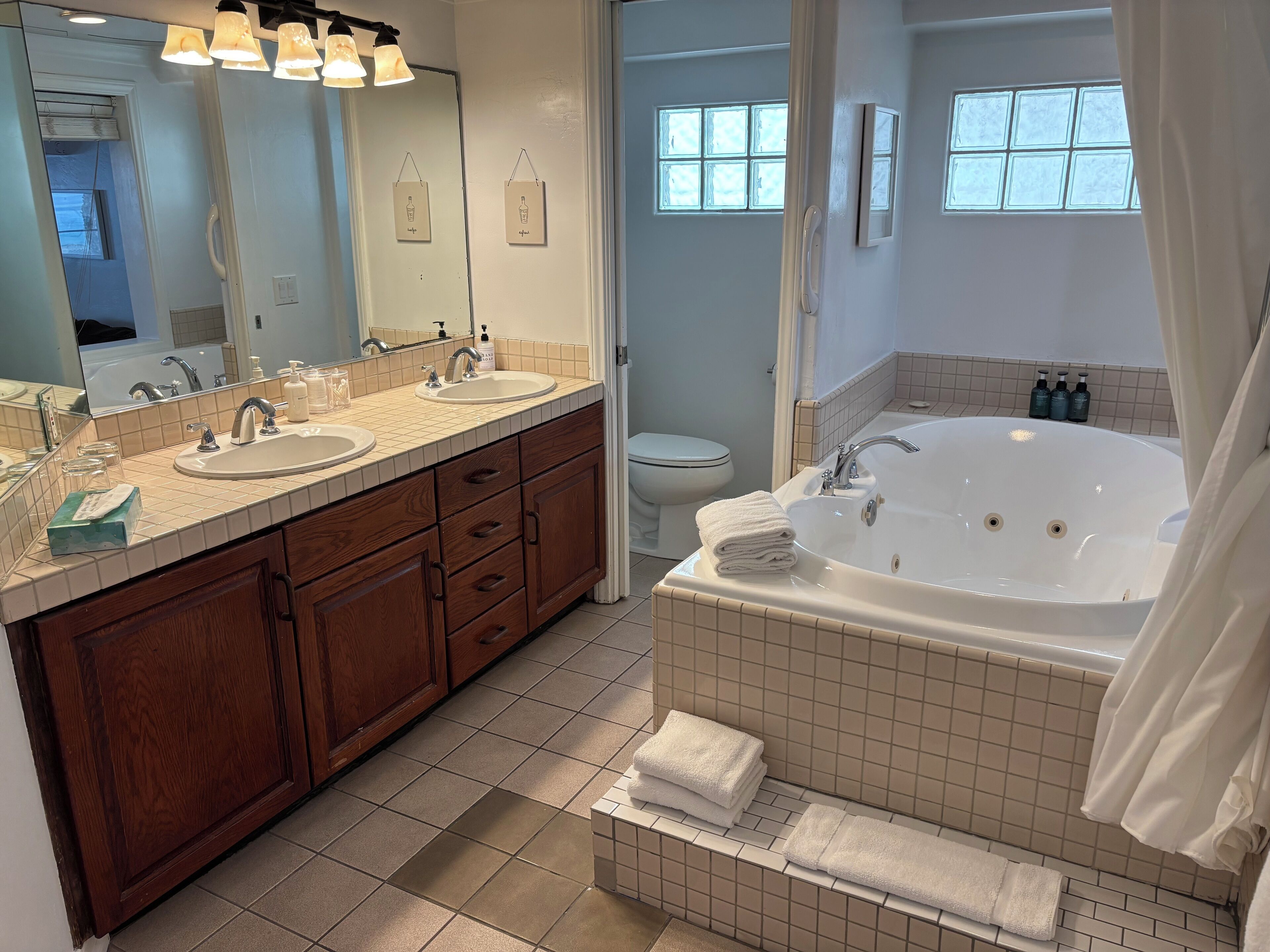A modern bathroom with two sinks, a large bathtub, and a toilet.