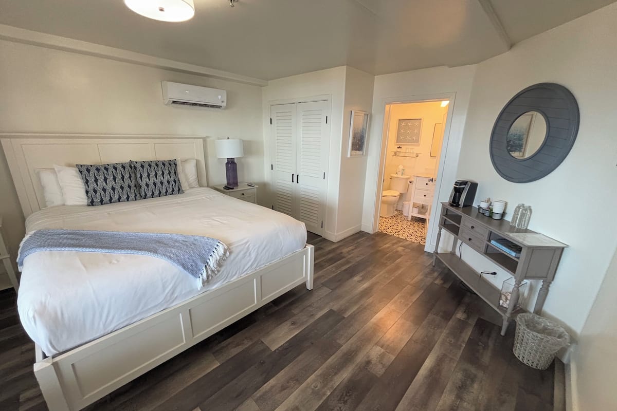 Um quarto com cama, mesa de cabeceira, luminária e cômoda com espelho.