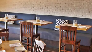 A restaurant interior with a brick wall, wooden tables and chairs, and a sign reading "SAN CLEMENTE". - Casa Tropicana (San Clemente)