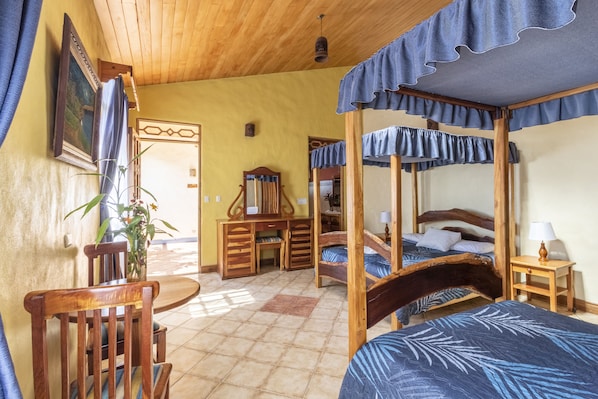 Une pièce avec un plafond en bois, un lit à baldaquin, un bureau, une chaise et une petite table avec une lampe.