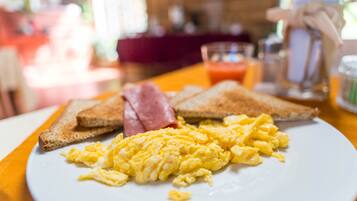 A breakfast plate with scrambled eggs, ham, and toast on a white plate.