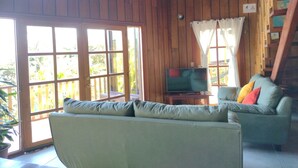 A wooden interior with a sofa, a television, and a staircase.
