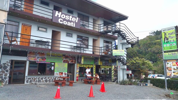 A hostel with a sign reading "Hostel Coati" and a restaurant named "La Soda Coati" in front. - Coati Place Hostel (Monteverde)