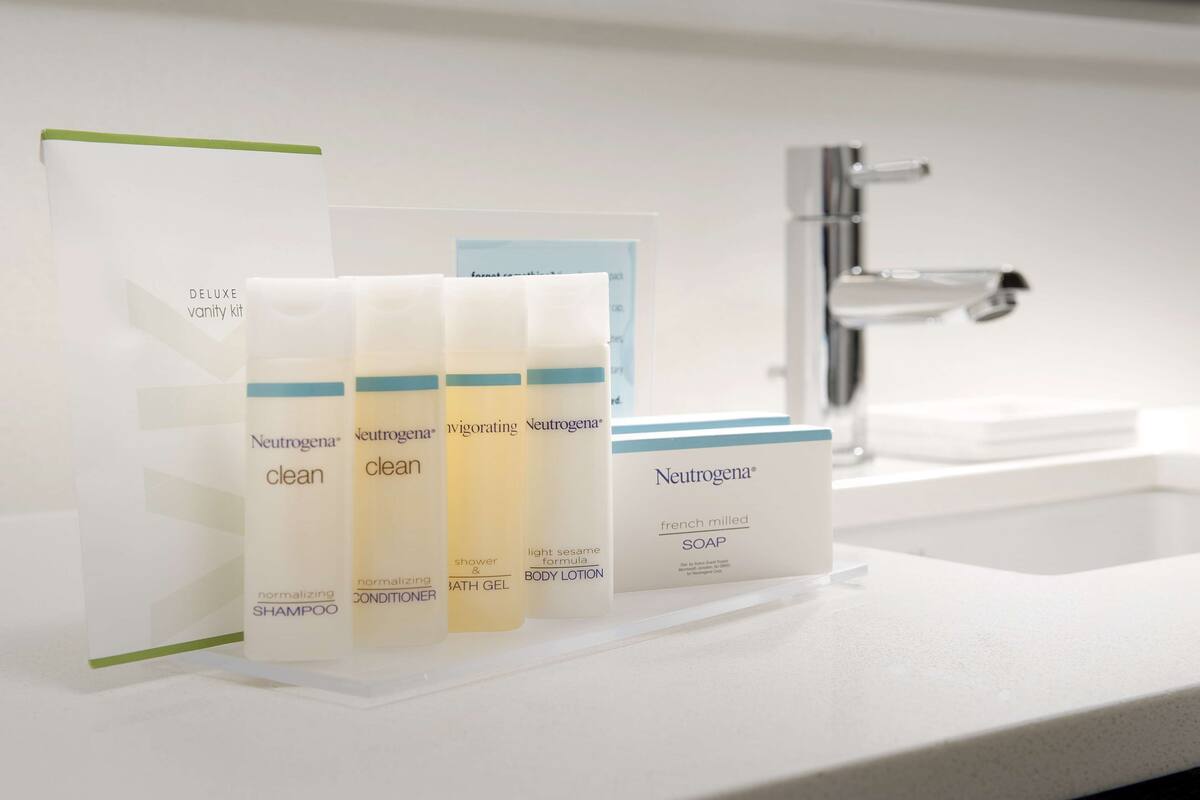Bany amb un rentamans blanc, un mirall i una estant amb productes Neutrogena.