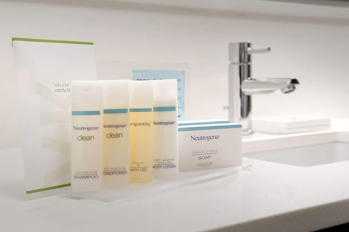 Un baño con un lavamanos blanco, un espejo y un estante con productos Neutrogena.