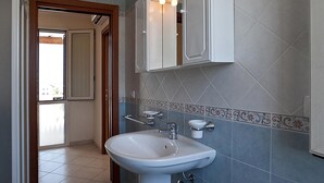 A bathroom with a white sink, blue tiles, and a mirror above it. - Casa del Sole Trilo A (Castrignano del Capo)