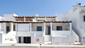 A white building with multiple balconies, a covered entrance, and a staircase leading to the upper floors. - Casa del Sole Trilo A (Castrignano del Capo)