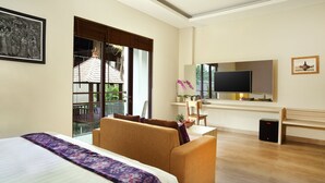 A hotel room with a bed, a sofa, a TV, a desk, and a window with a view of a building. - The Evitel Resort Ubud (Ubud)